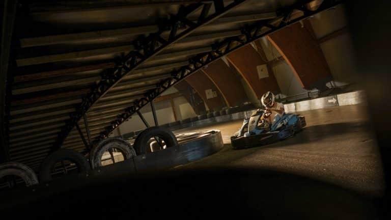 Pilote de karting sous un pont métallique.