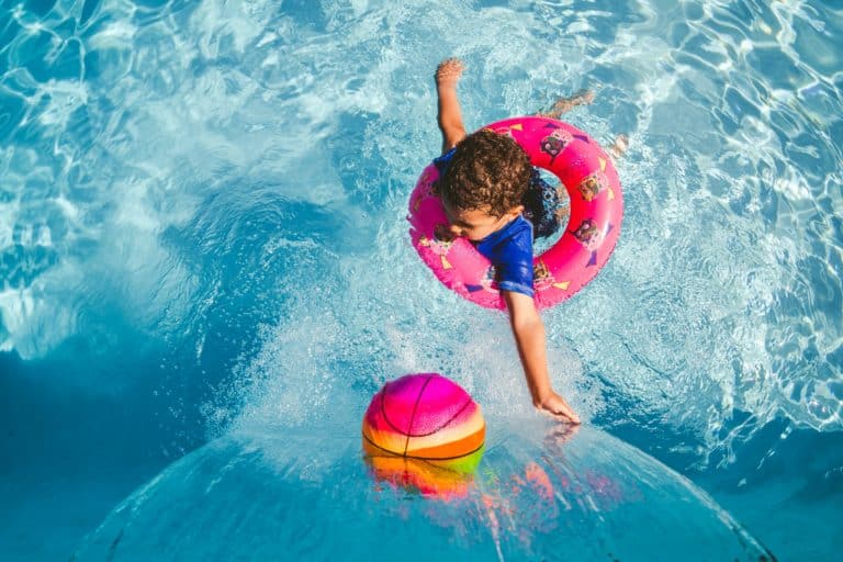 Enfant joue avec une bouée dans la piscine.
