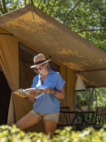 Tente aménagé de camping avec une femme qui lis un livre