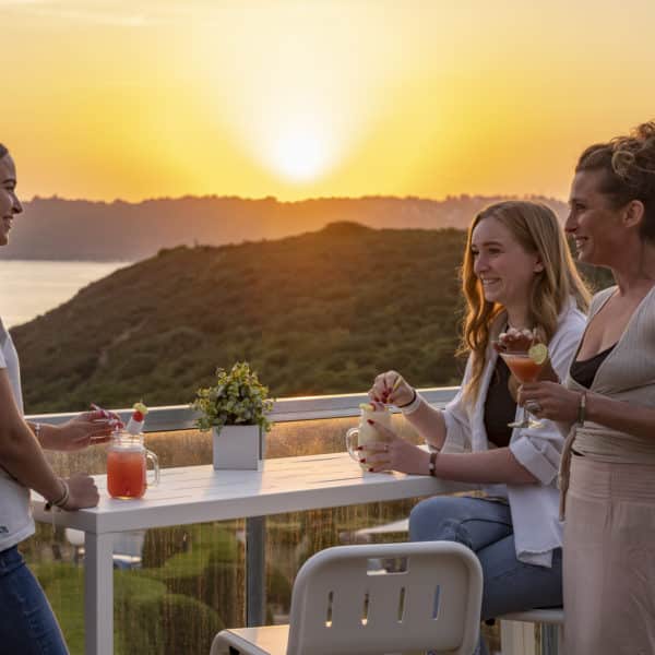 Trois femmes qui échangent autour d'un verre au coucher du soleil